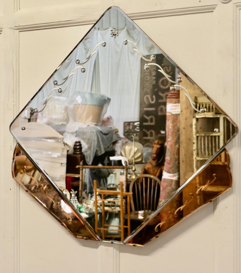 A diamond-shaped Art Deco wall mirror featuring a clear main glass panel with etched scroll motifs and angled peach-tinted glass lower borders. View V