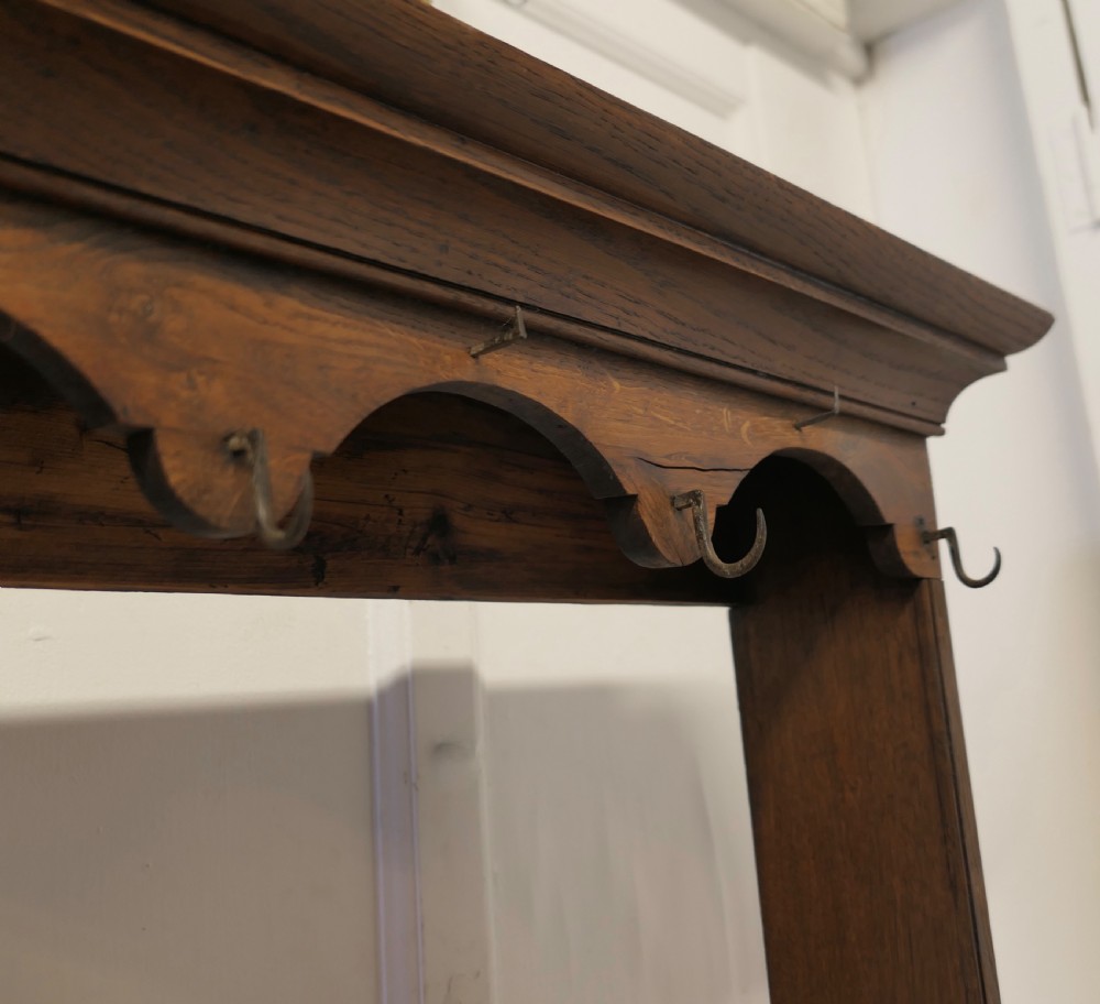 A Georgian country oak dresser featuring an open tiered plate rack set above multiple drawer compartments, arched aprons, and an open pot shelf at the base. View VII