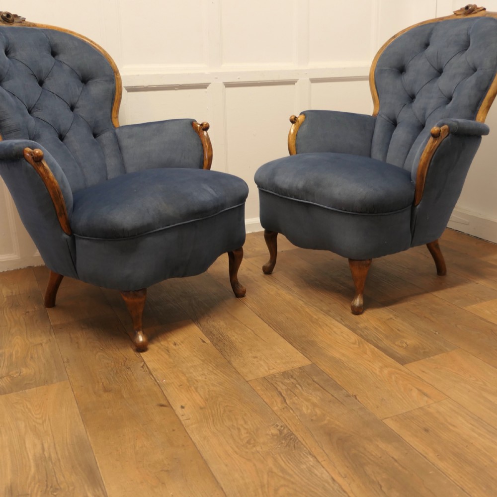 A pair of French salon armchairs upholstered in blue button-backed velvet with carved walnut frames and short wooden legs. View II