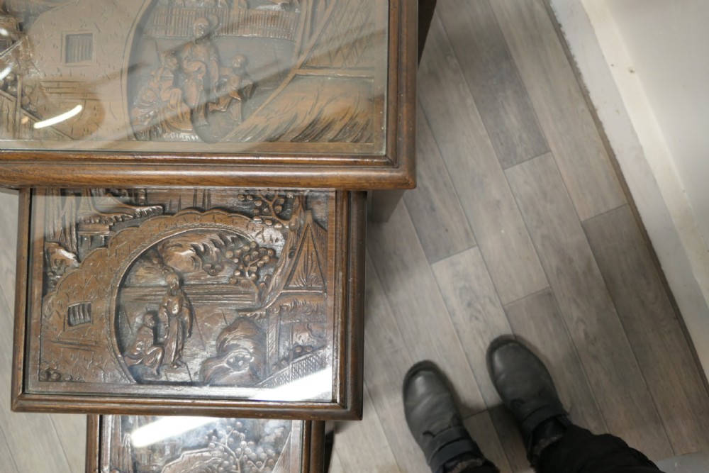 A set of four dark brown hardwood nesting tables featuring carved pierced aprons and glass-inset tops. View VIII