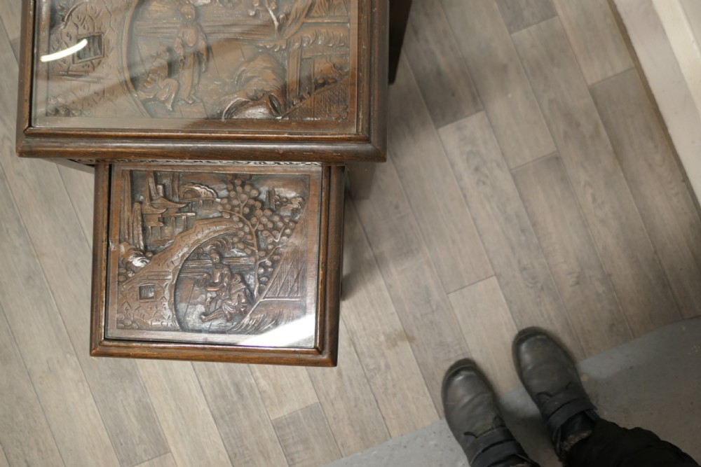 A set of four dark brown hardwood nesting tables featuring carved pierced aprons and glass-inset tops. View IX