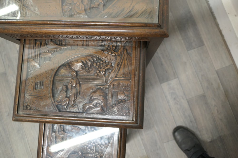 A set of four dark brown hardwood nesting tables featuring carved pierced aprons and glass-inset tops. View X