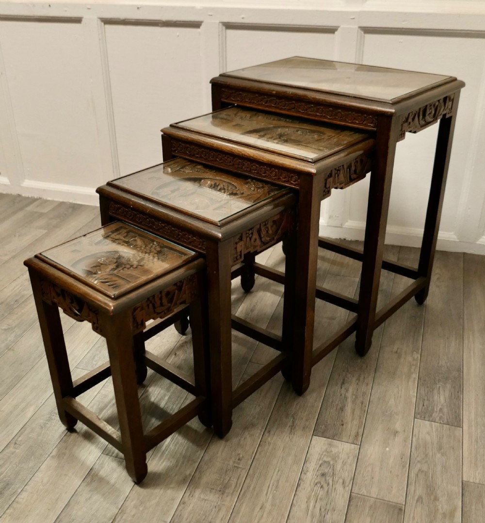 A set of four dark brown hardwood nesting tables featuring carved pierced aprons and glass-inset tops. View XI