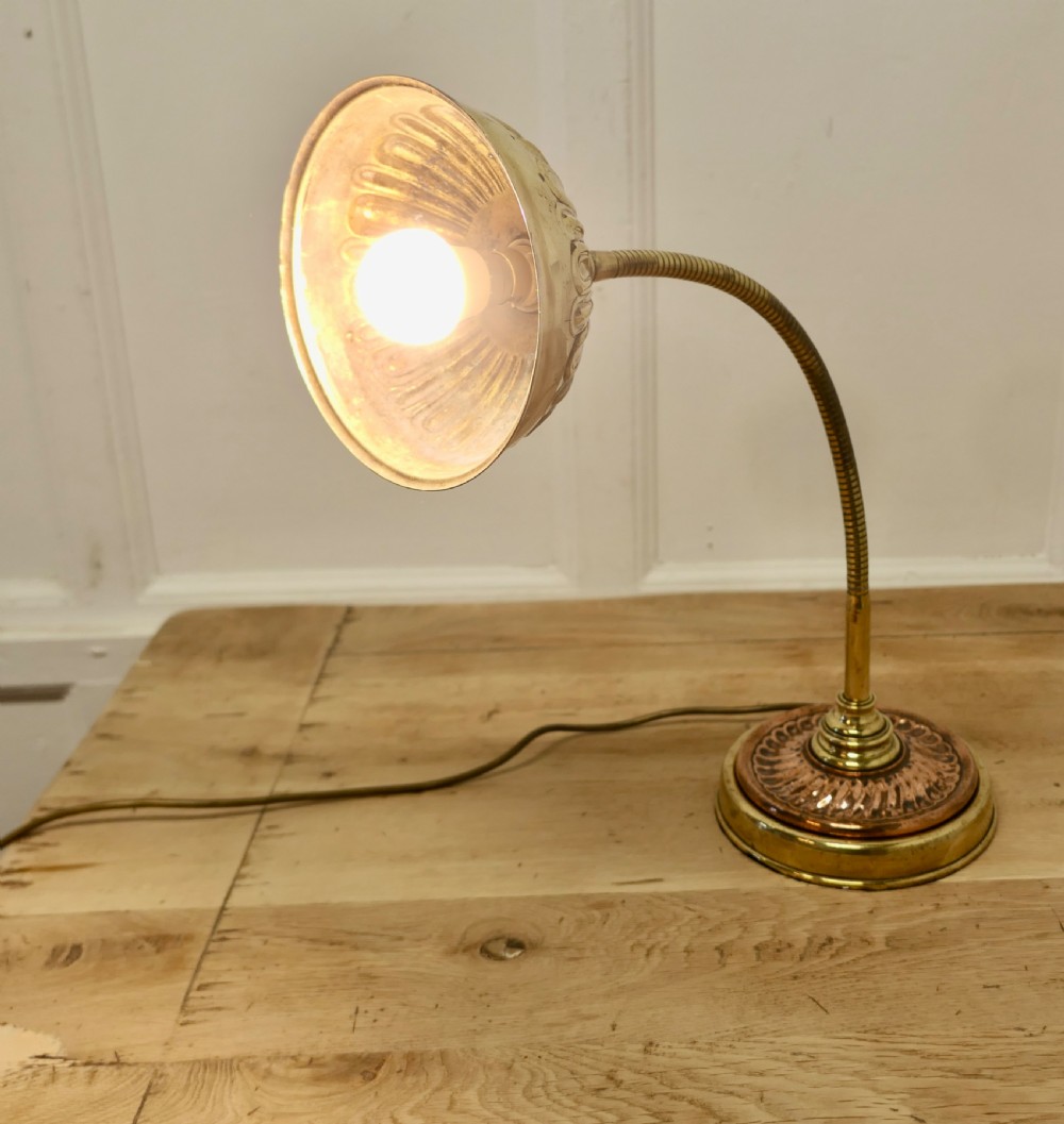 An Art Deco desk lamp featuring a flexible gooseneck arm, a ribbed brass shade, and a circular copper and brass base. View V