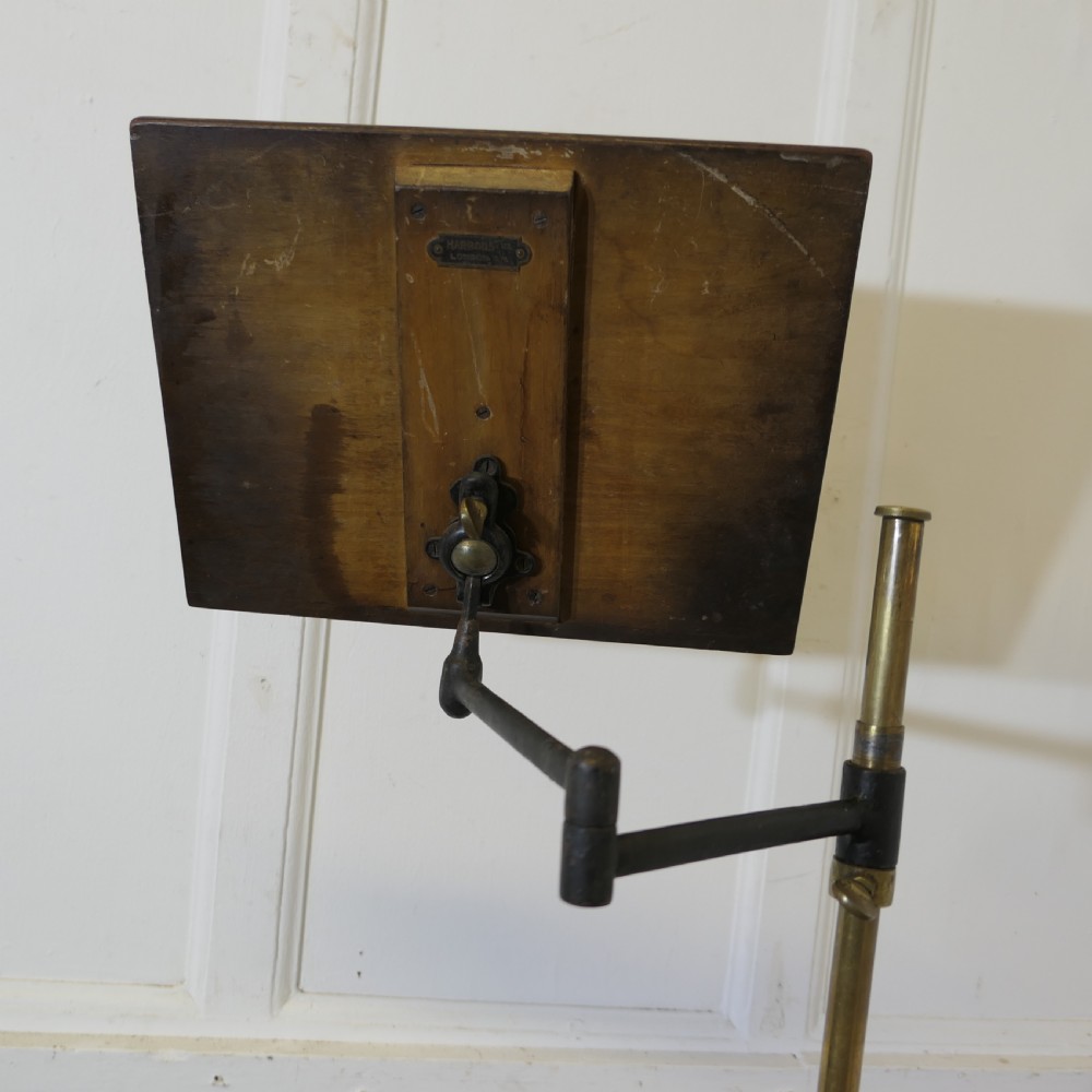 A floor-standing adjustable brass reading stand featuring a dark wooden tilted book rest, an articulated extension arm, and a four-legged cast iron claw foot base. View IV