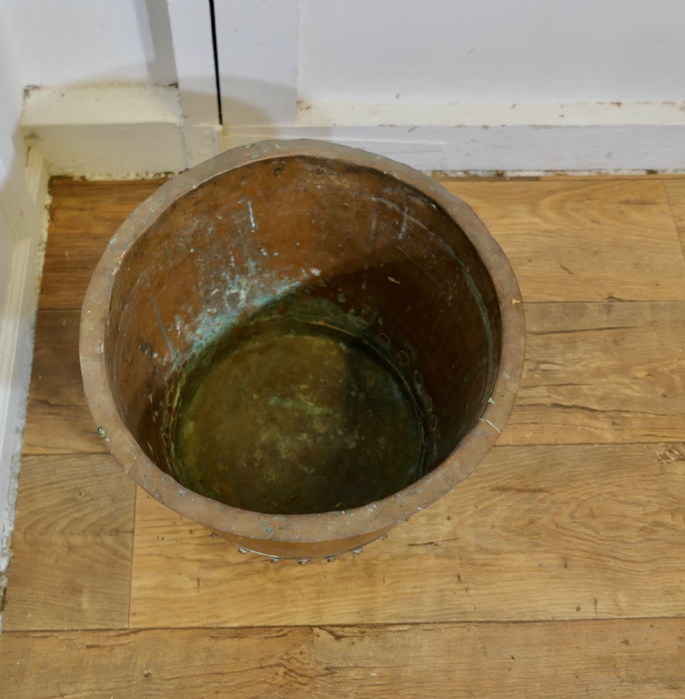 A cylindrical early nineteenth-century hand-hammered copper tub featuring a flared upper lip and a base reinforced with a riveted metal band. View V