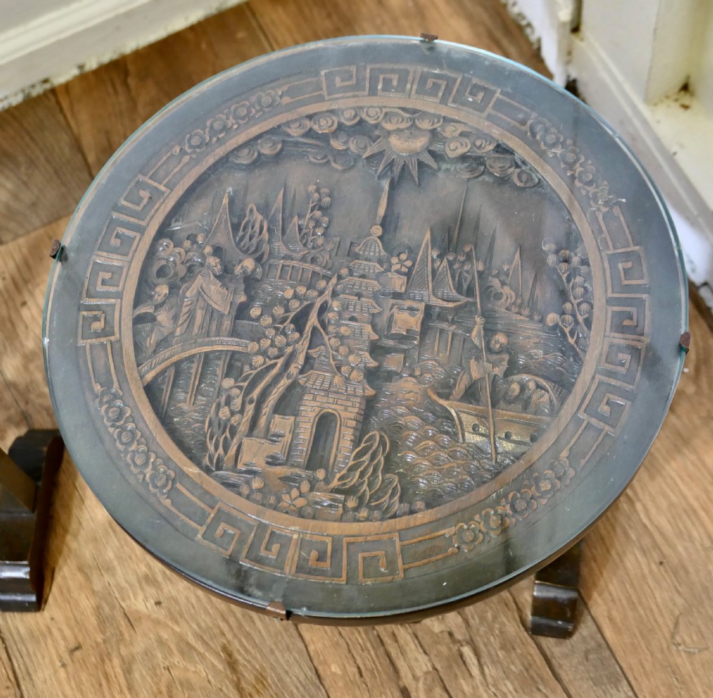 A pair of circular dark wood side tables featuring relief-carved landscape panels beneath fitted glass tops. View II