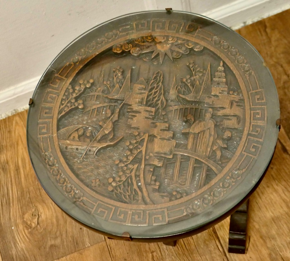 A pair of circular dark wood side tables featuring relief-carved landscape panels beneath fitted glass tops. View III