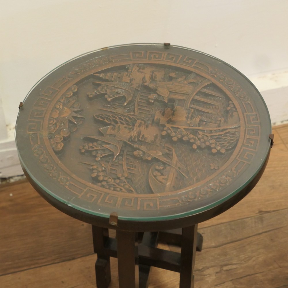 A pair of circular dark wood side tables featuring relief-carved landscape panels beneath fitted glass tops. View IV