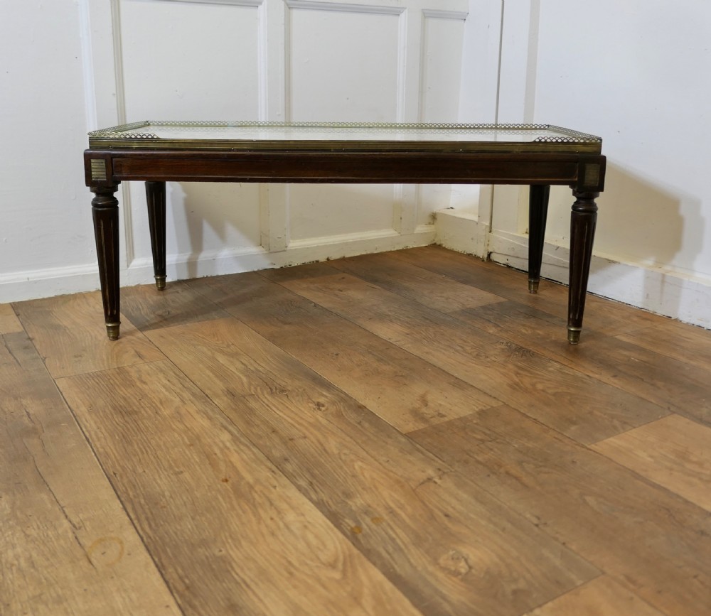 A French nineteenth-century rectangular dark wood low table with fluted tapered legs, brass feet, and a pierced brass gallery around the top edge.