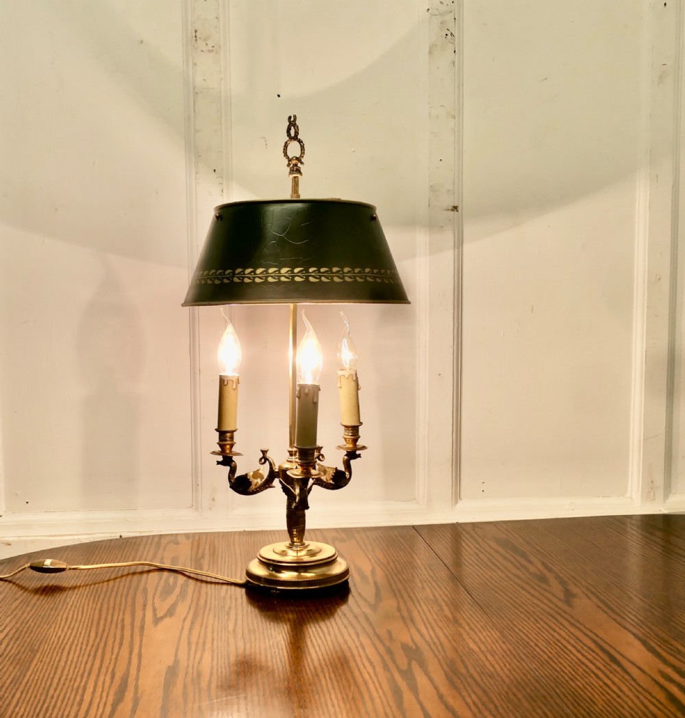 A French toleware and brass bouillotte desk lamp featuring three candle-style lights under a dark green painted metal shade with gilt leaf decoration.