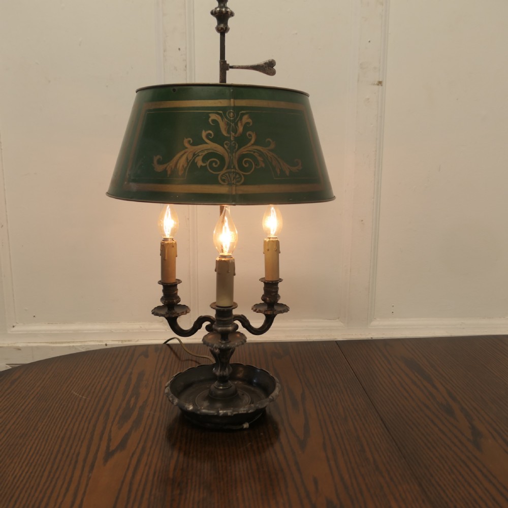A silver-plated French bouillotte desk lamp featuring a green tole shade with gold scroll detailing and three candlestick lights set in a dished base. View II
