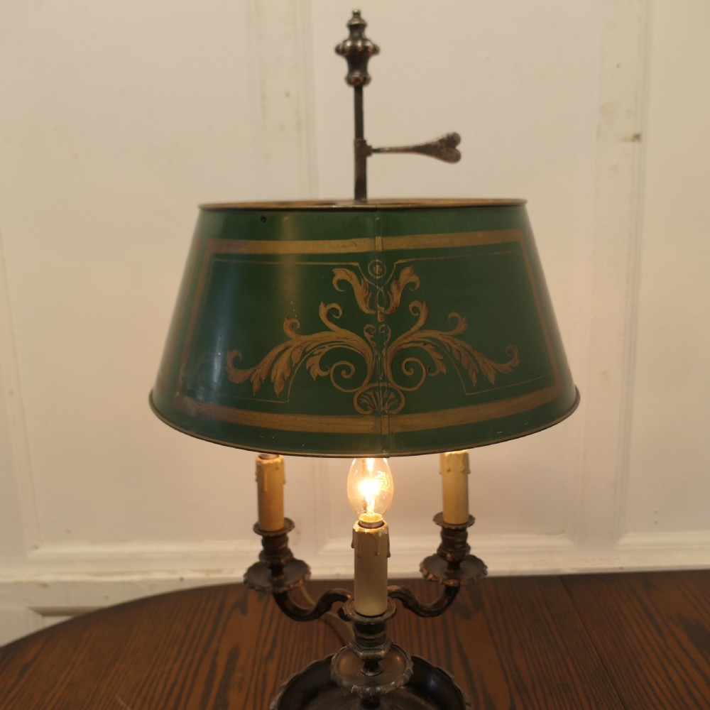 A silver-plated French bouillotte desk lamp featuring a green tole shade with gold scroll detailing and three candlestick lights set in a dished base. View III