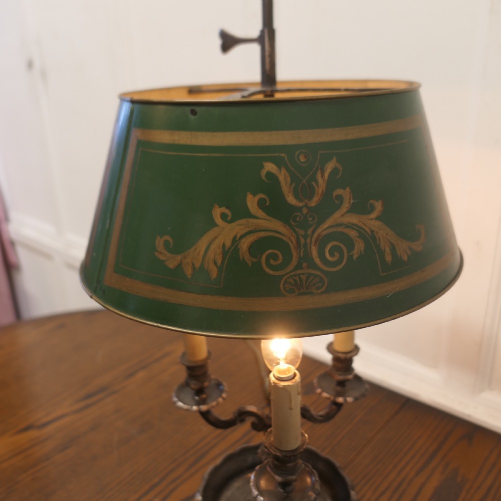 A silver-plated French bouillotte desk lamp featuring a green tole shade with gold scroll detailing and three candlestick lights set in a dished base. View VI