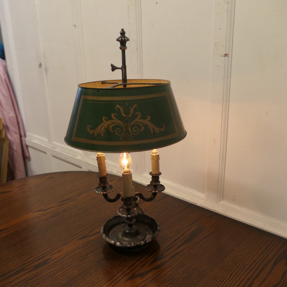 A silver-plated French bouillotte desk lamp featuring a green tole shade with gold scroll detailing and three candlestick lights set in a dished base. View VII