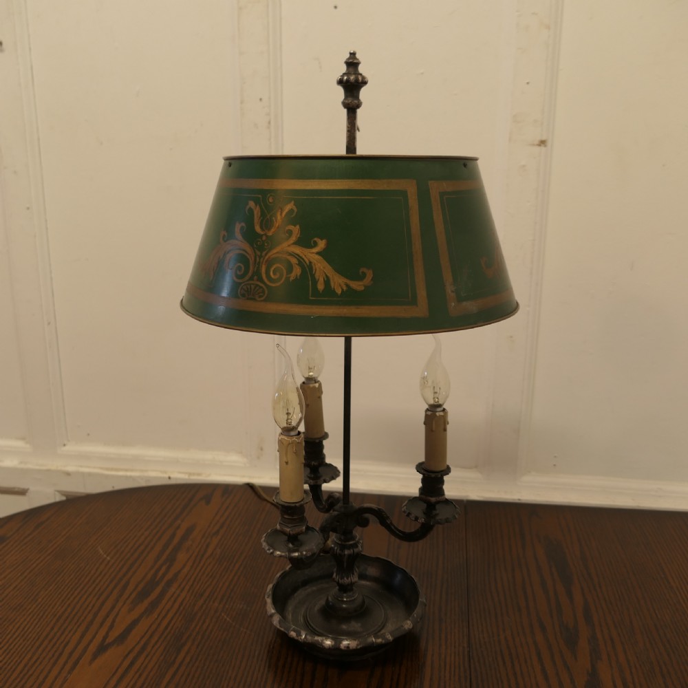 A silver-plated French bouillotte desk lamp featuring a green tole shade with gold scroll detailing and three candlestick lights set in a dished base. View VIII