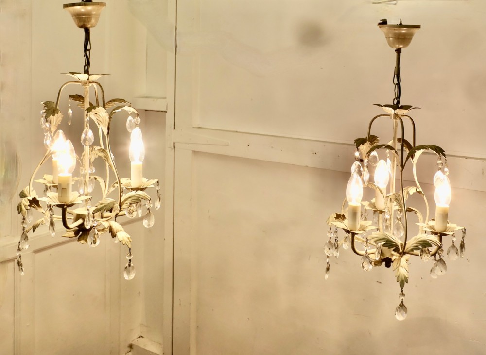 A pair of white painted metal open basket chandeliers featuring foliate leaf motifs, candle bulb holders, and suspended glass droplets. View II