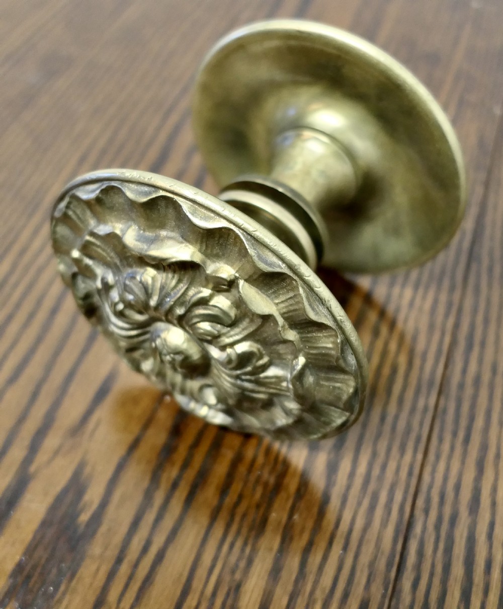 A circular embossed brass door knob featuring an intricate floral and scrollwork design. View II