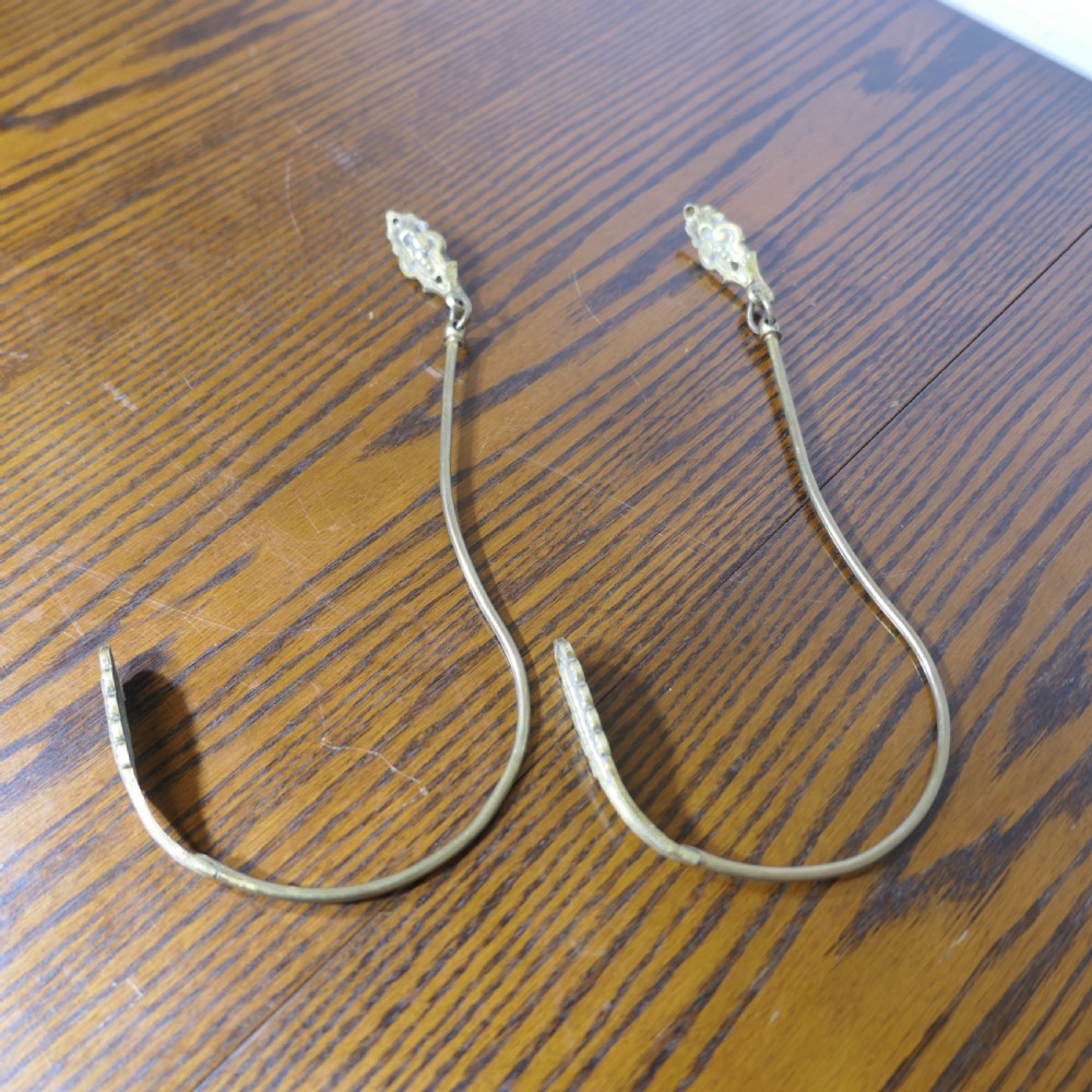A pair of large 19th-century French brass curtain tiebacks featuring curved arms with decorative terminal plates.