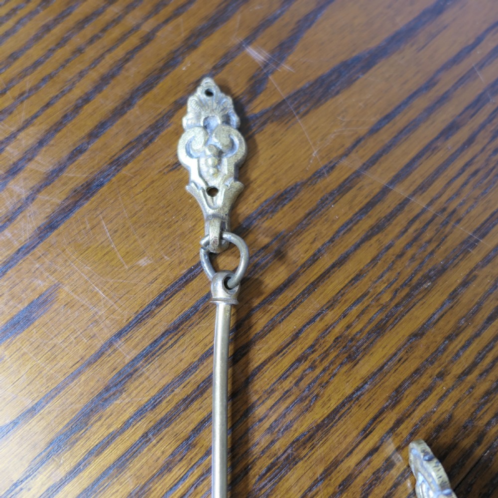 A pair of large 19th-century French brass curtain tiebacks featuring curved arms with decorative terminal plates. View II