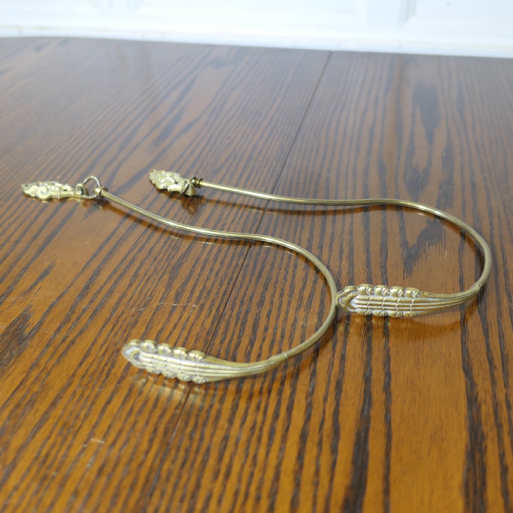 A pair of large 19th-century French brass curtain tiebacks featuring curved arms with decorative terminal plates. View III