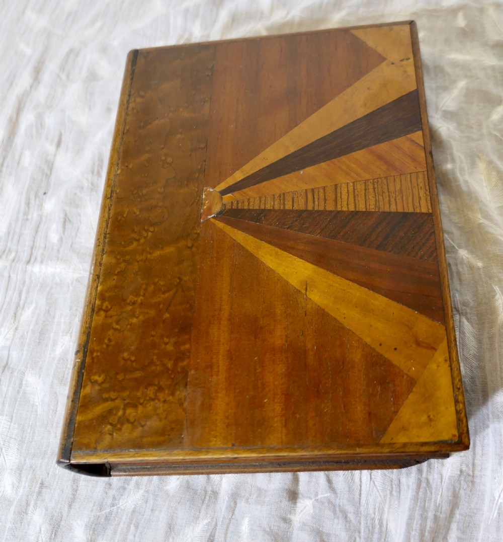 An Art Deco book-shaped wooden secret safe featuring a geometric sunburst parquetry design crafted from contrasting timber veneers.