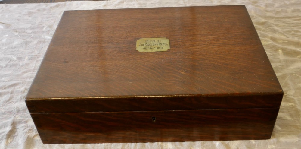 A rectangular dark oak presentation box featuring a keyhole on the front panel and an engraved brass plaque on the top lid.
