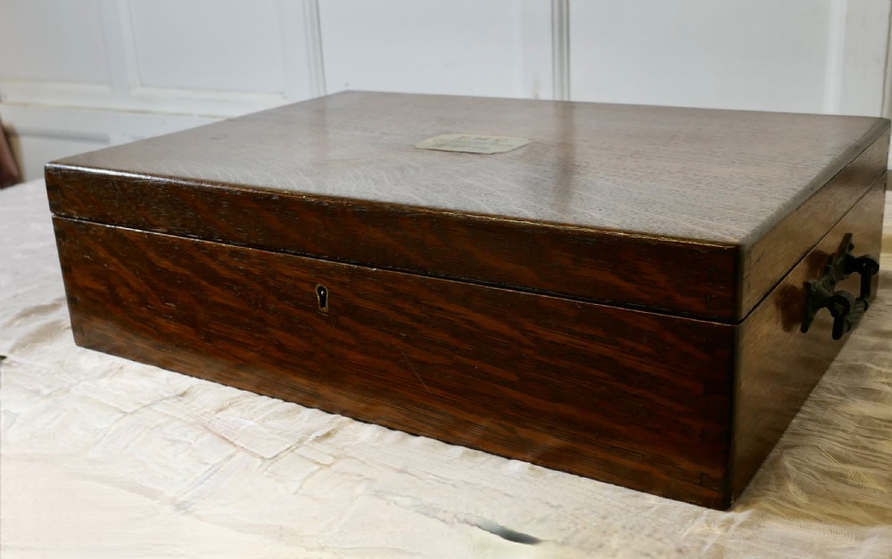 A rectangular dark oak presentation box featuring a keyhole on the front panel and an engraved brass plaque on the top lid. View III