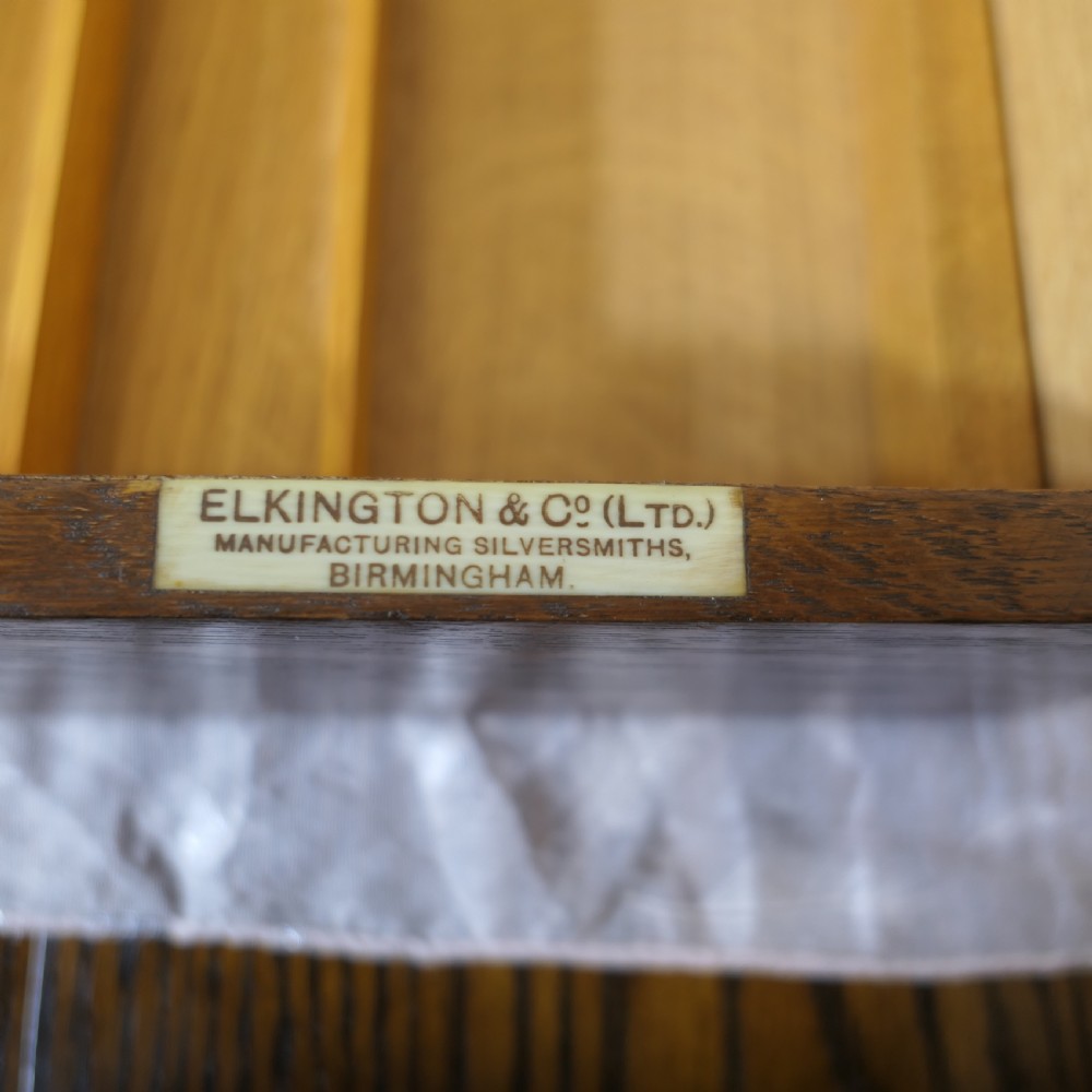A rectangular dark oak presentation box featuring a keyhole on the front panel and an engraved brass plaque on the top lid. View V