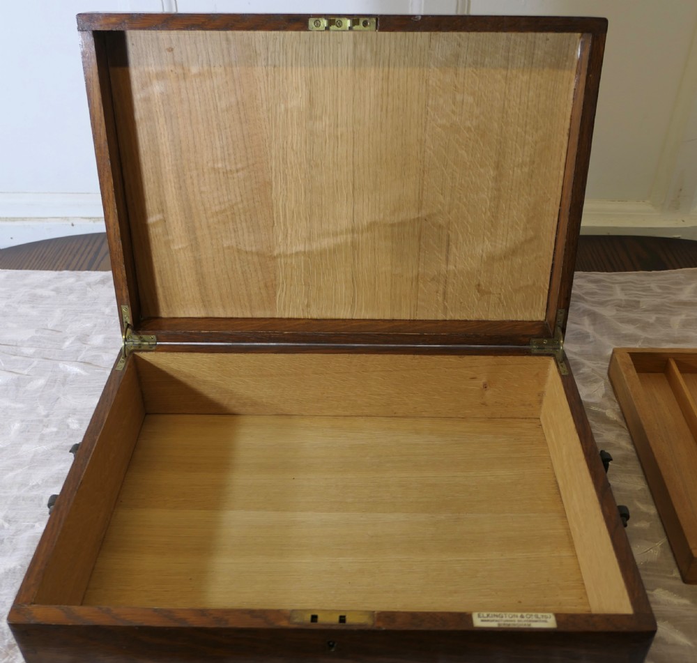 A rectangular dark oak presentation box featuring a keyhole on the front panel and an engraved brass plaque on the top lid. View VI