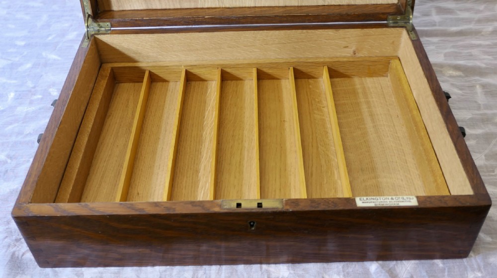 A rectangular dark oak presentation box featuring a keyhole on the front panel and an engraved brass plaque on the top lid. View VII