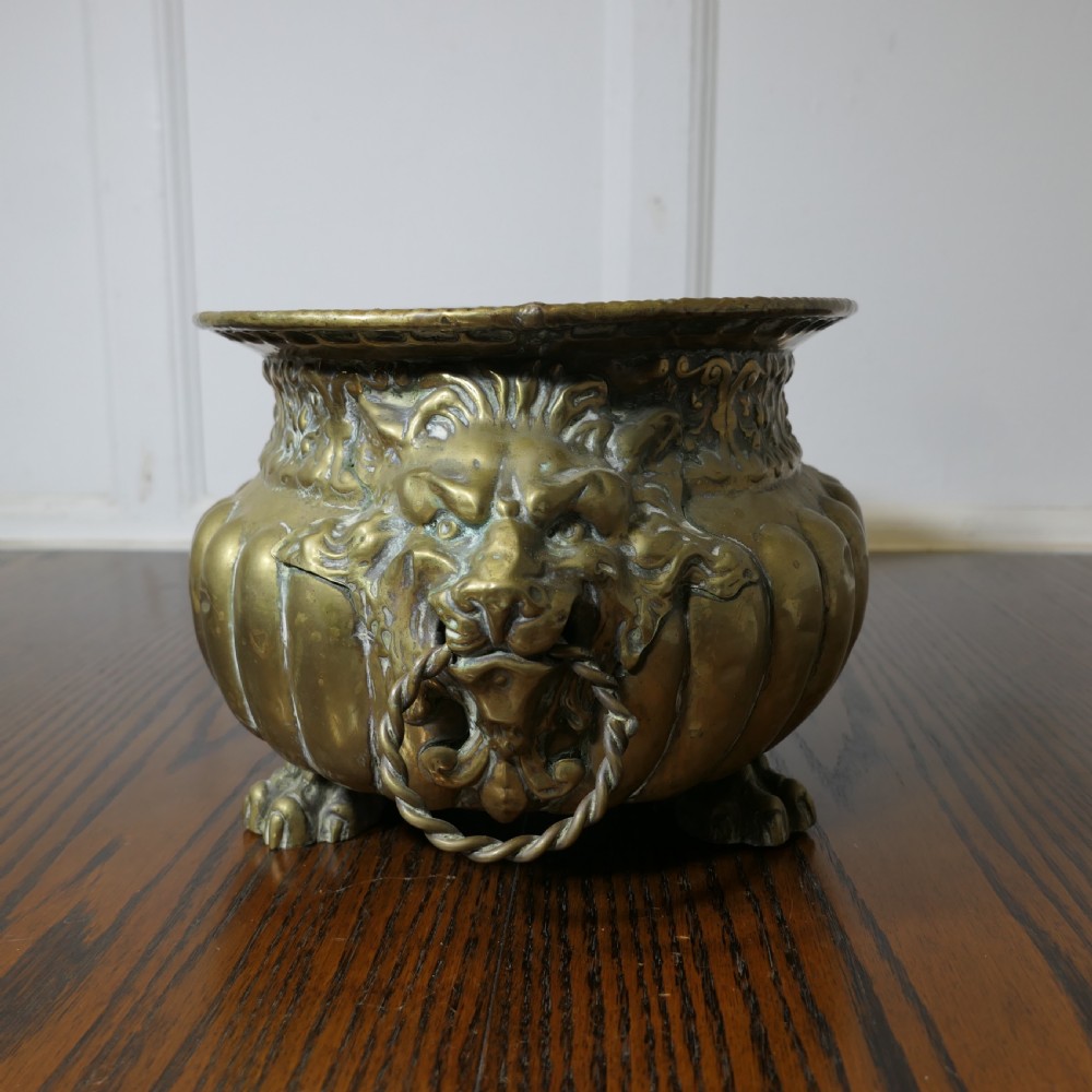 An oval antique brass jardiniere featuring gadrooned lower detail, lion mask handles with drop rings, paw feet, and a removable internal metal liner. View III
