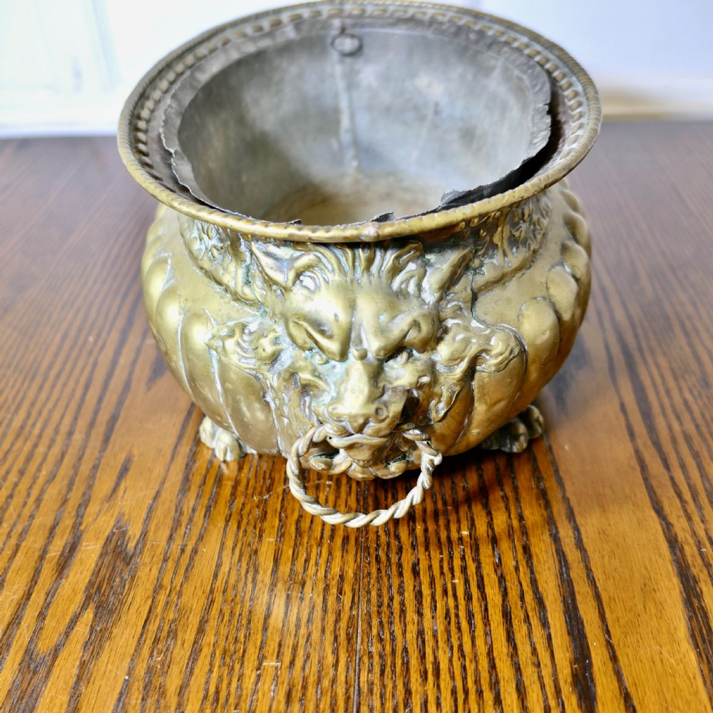An oval antique brass jardiniere featuring gadrooned lower detail, lion mask handles with drop rings, paw feet, and a removable internal metal liner. View IV