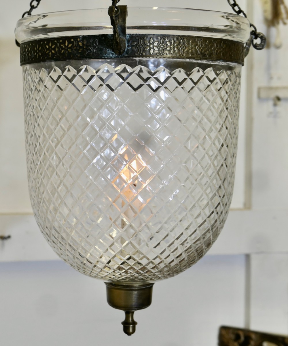 A diamond-cut crystal bell jar pendant light suspended by metal chains with a top glass smoke shade and brass rim band. View II