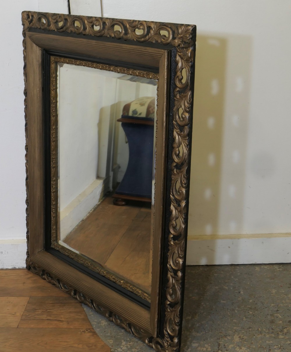 A large rectangular wall mirror featuring an ornate dark gilt frame with openwork scroll carving, a reeded inner moulding, and dark accents. View III