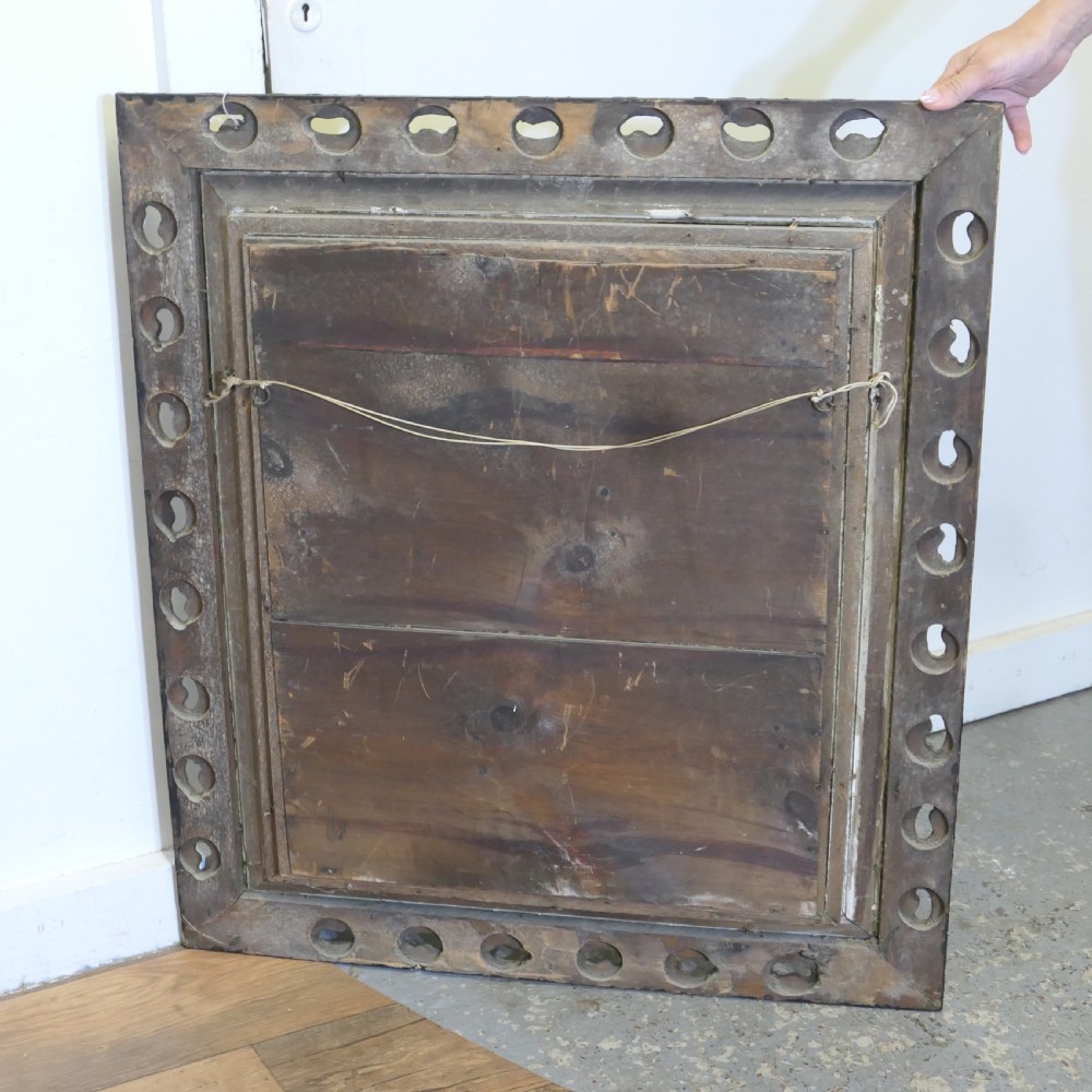 A large rectangular wall mirror featuring an ornate dark gilt frame with openwork scroll carving, a reeded inner moulding, and dark accents. View V