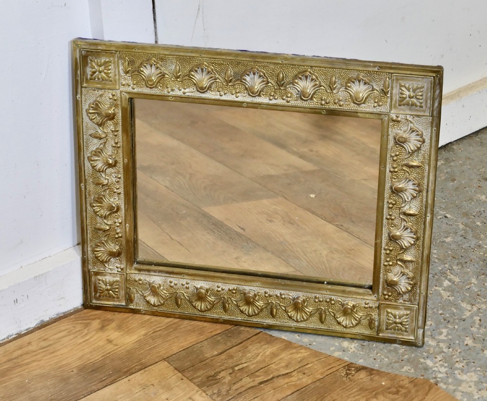 A rectangular wall mirror featuring an embossed brass frame decorated with shell motifs and stippled texture. View III