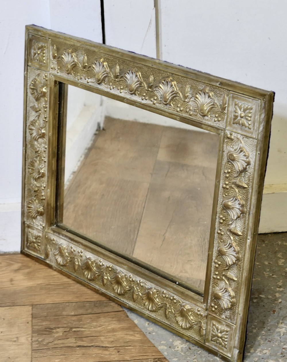 A rectangular wall mirror featuring an embossed brass frame decorated with shell motifs and stippled texture. View IV