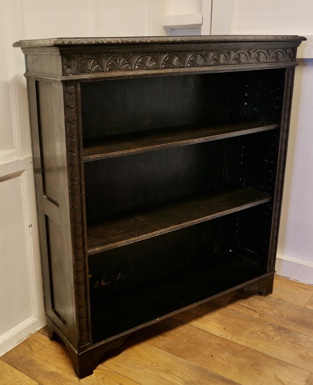 A dark carved oak open bookcase featuring a decorative carved frieze and three open shelves. View III