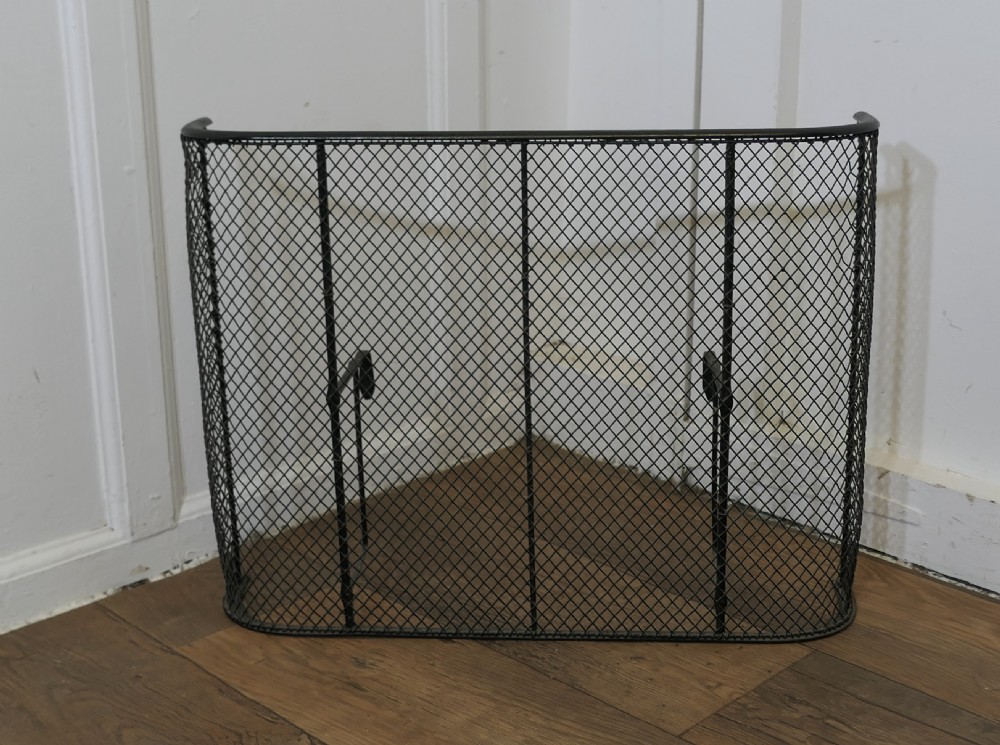A black painted iron Victorian nursery fire guard featuring a rounded wire mesh frame with vertical support rods.