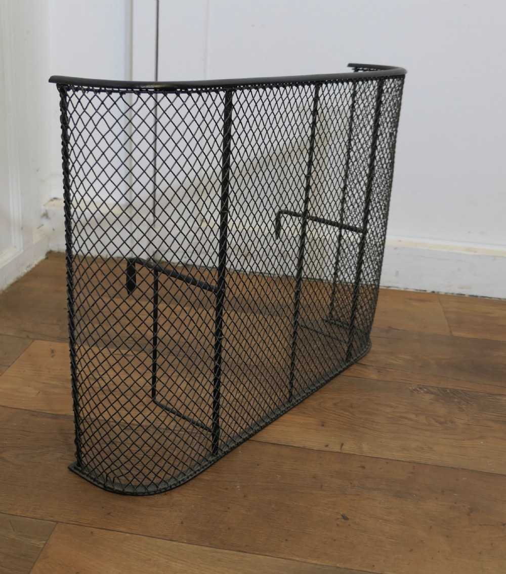 A black painted iron Victorian nursery fire guard featuring a rounded wire mesh frame with vertical support rods. View V