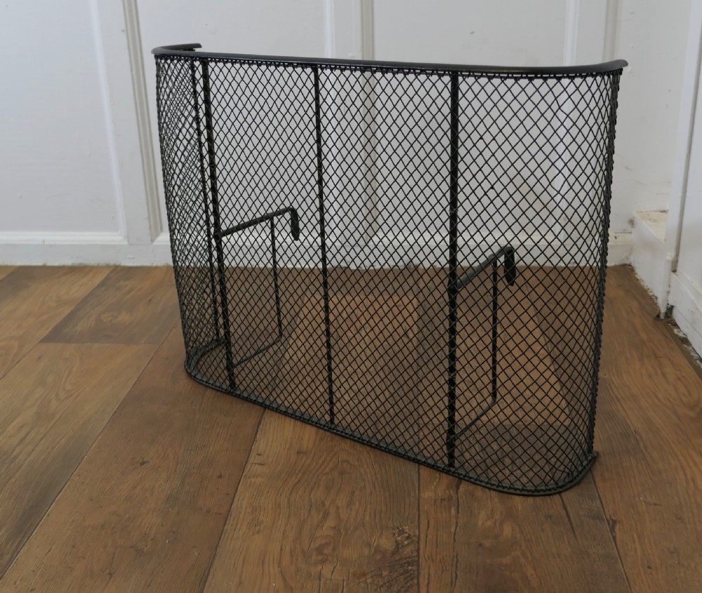 A black painted iron Victorian nursery fire guard featuring a rounded wire mesh frame with vertical support rods. View VI