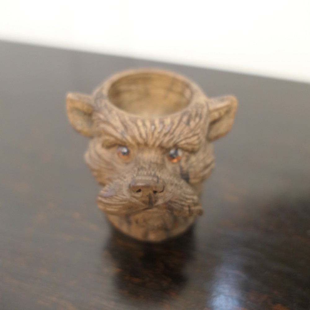 A hand-carved wooden head of a Scottish terrier with glass eyes and carved fur details. View II