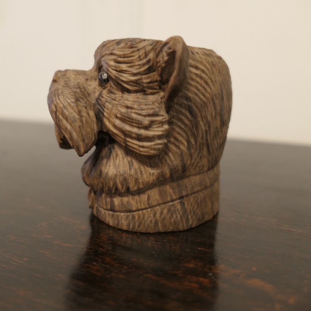 A hand-carved wooden head of a Scottish terrier with glass eyes and carved fur details. View III