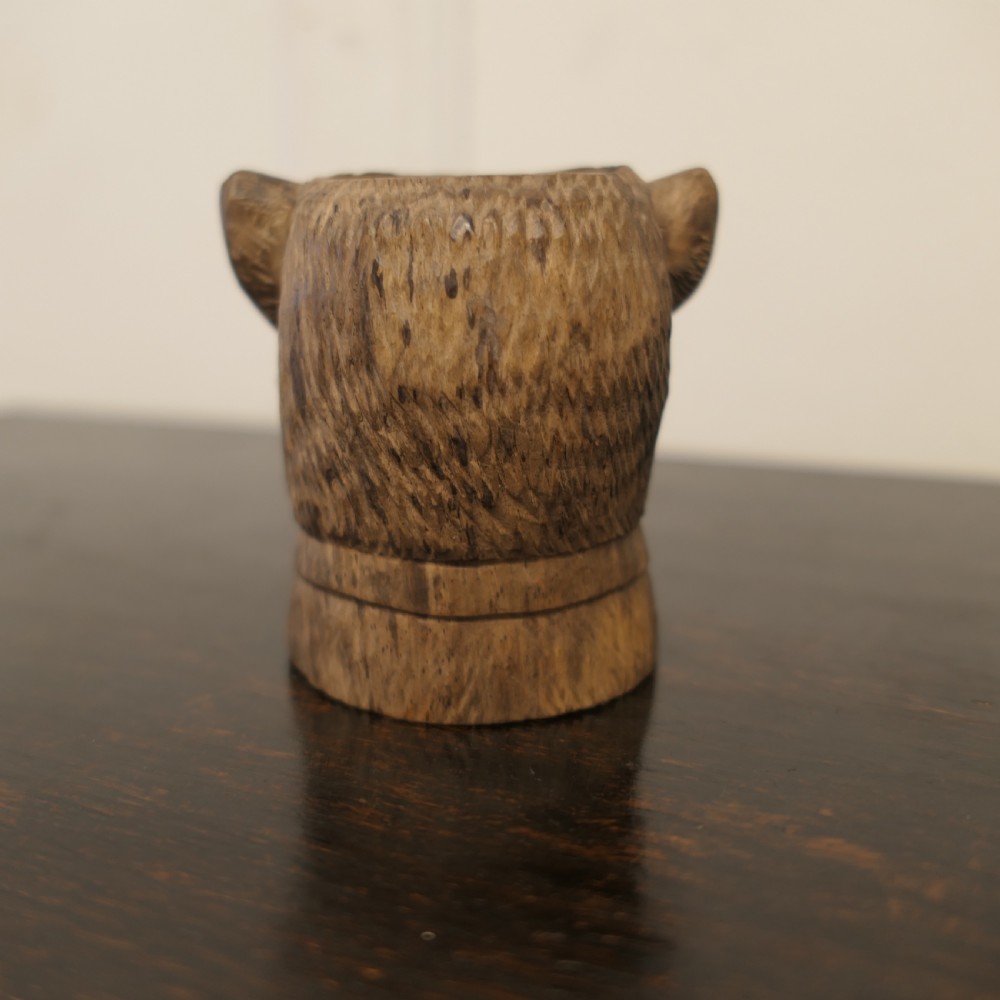 A hand-carved wooden head of a Scottish terrier with glass eyes and carved fur details. View V