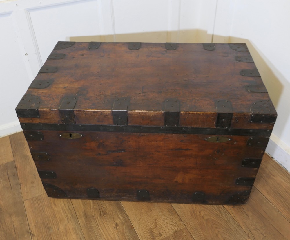 A large dark wood travel trunk with heavy black iron straps, corner metalwork, and two brass keyhole plates. View II