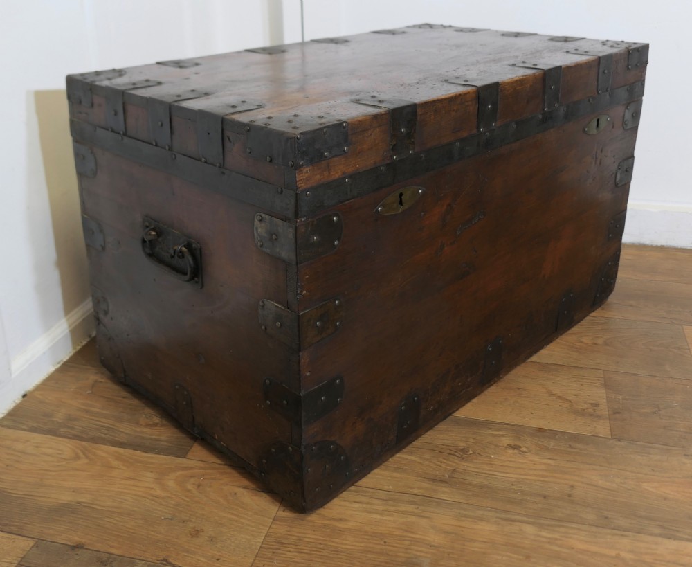 A large dark wood travel trunk with heavy black iron straps, corner metalwork, and two brass keyhole plates. View III