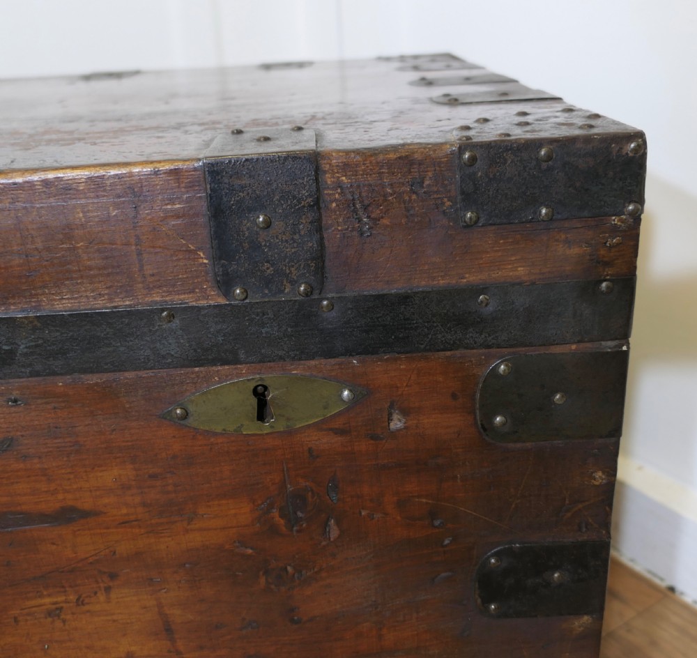 A large dark wood travel trunk with heavy black iron straps, corner metalwork, and two brass keyhole plates. View IV
