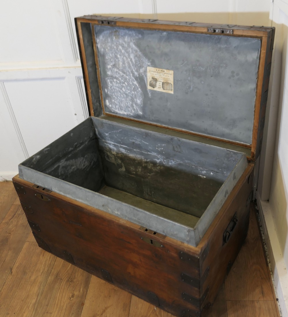 A large dark wood travel trunk with heavy black iron straps, corner metalwork, and two brass keyhole plates. View V
