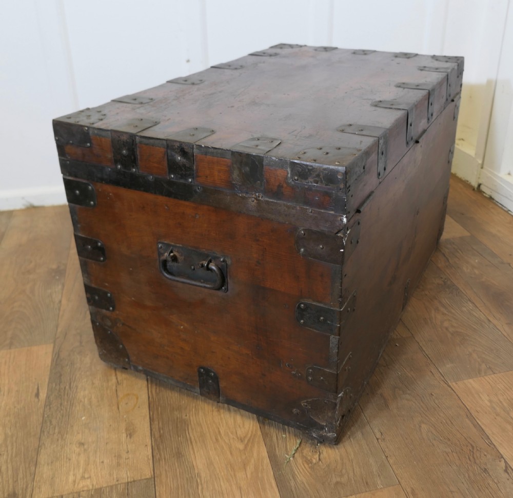 A large dark wood travel trunk with heavy black iron straps, corner metalwork, and two brass keyhole plates. View VII